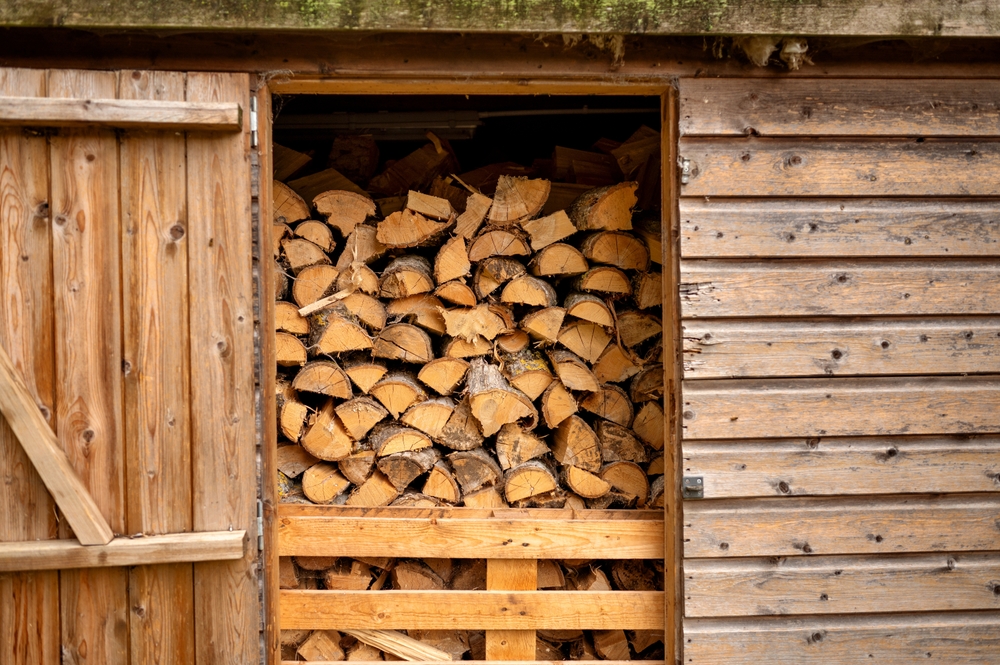Neatly stacked firewood inside a wooden shed. for winter use.